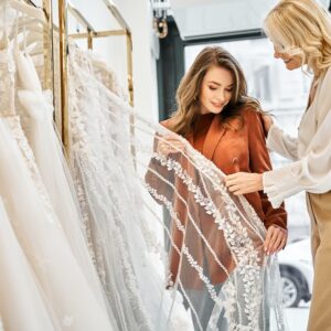 Two,Women,,A,Young,Bride,And,Her,Mother,,Admiring,Wedding Wedding Dress Shopping